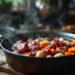Civet de sanglier en préparation dans une cuisine rustique, avec de la viande marinée au vin rouge, des oignons, des carottes et un bouquet garni, sur une table en bois.